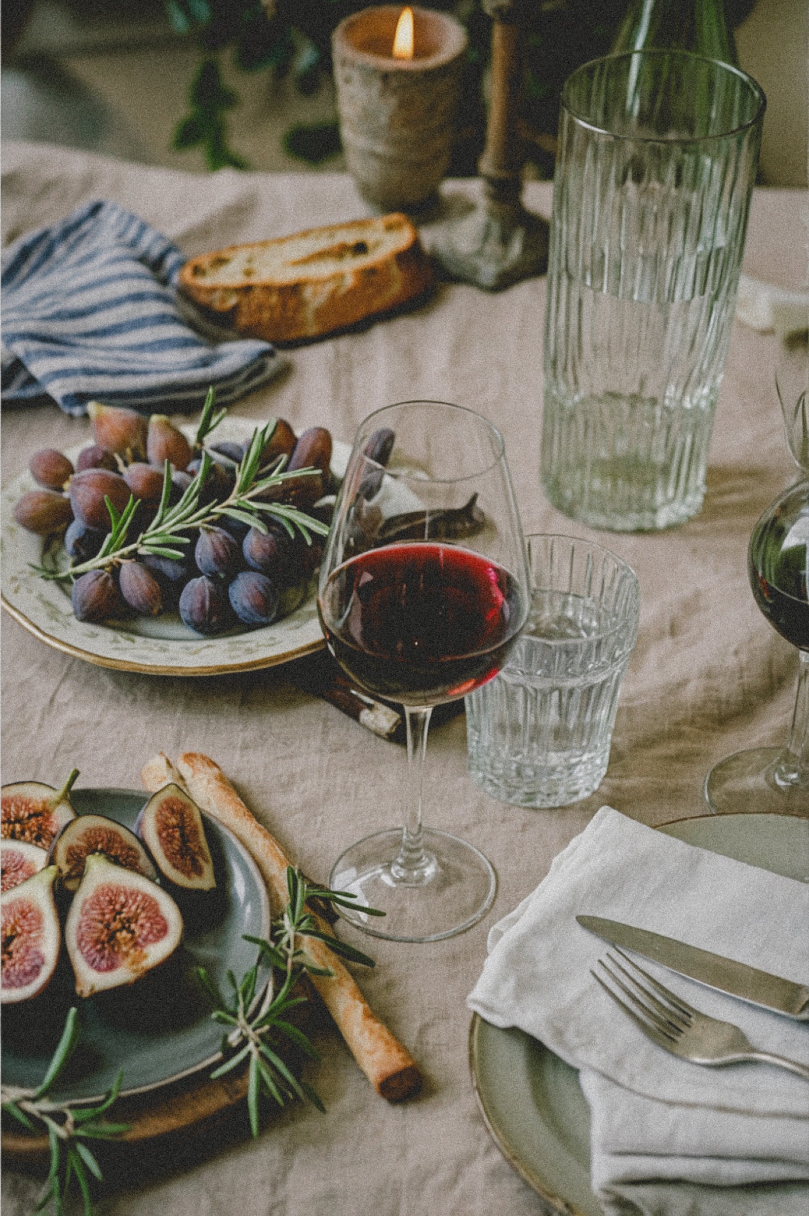 Figs, wine, bread and candles on a sunlit table