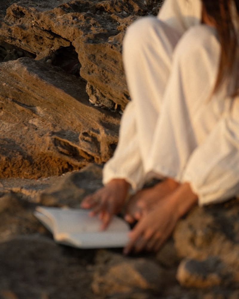 A woman journaling on sun-warmed rocks