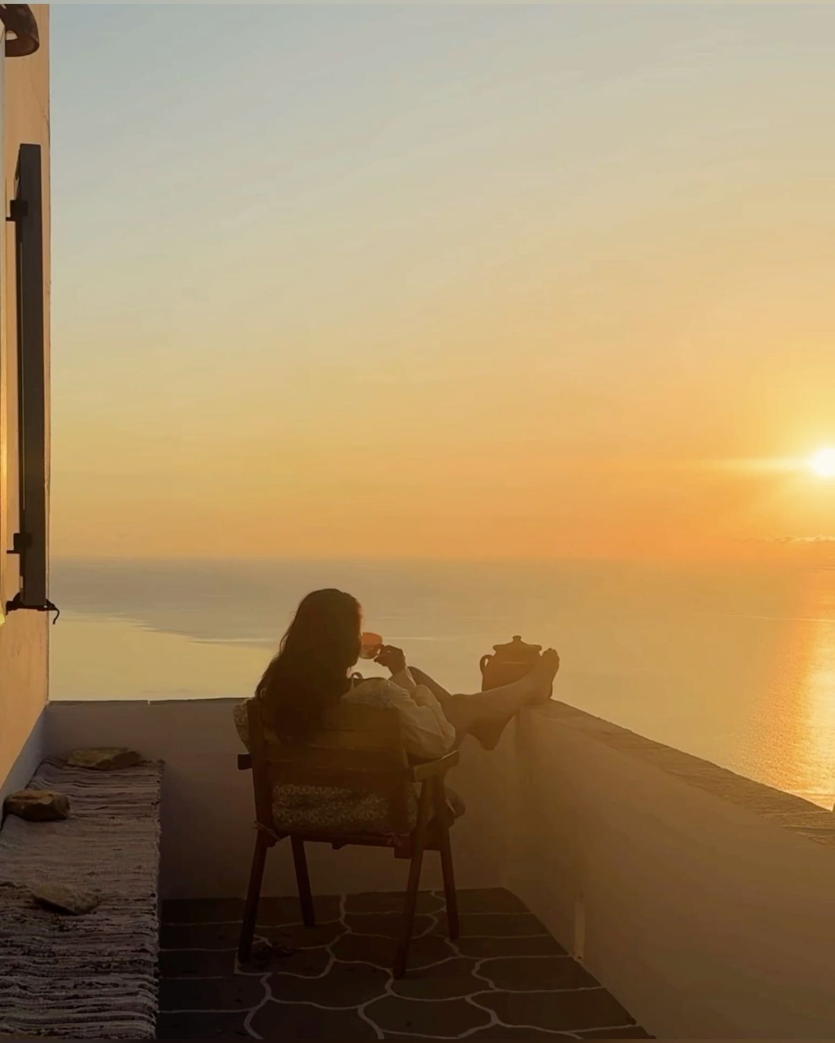 A woman looking out at a glowing ocean sunset